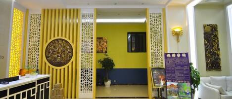 A hotel lobby with a reception desk, a seating area, and a decorative wall.