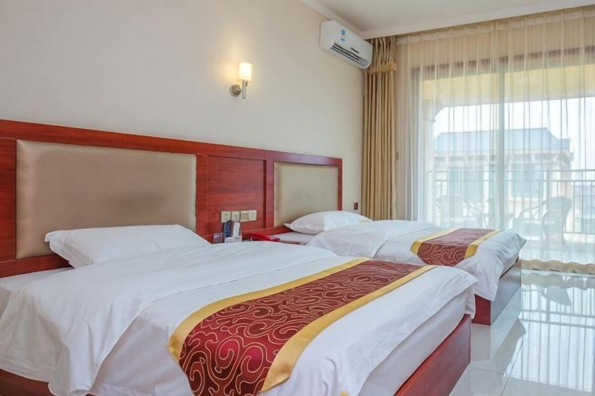 Une chambre d’hôtel avec deux lits, une tête de lit en bois, une table de chevet et une fenêtre avec des rideaux.