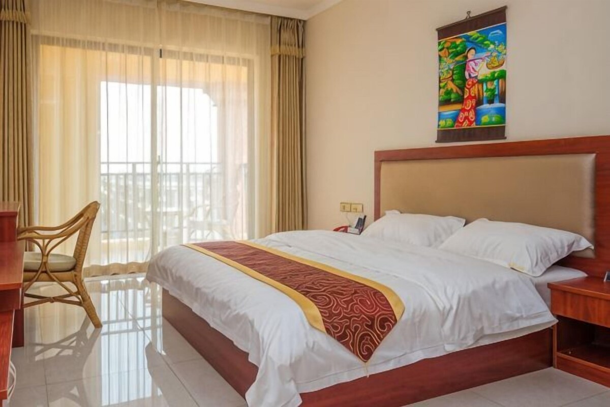 Une chambre d’hôtel avec un grand lit, une chaise, une table de chevet et un tableau au mur.