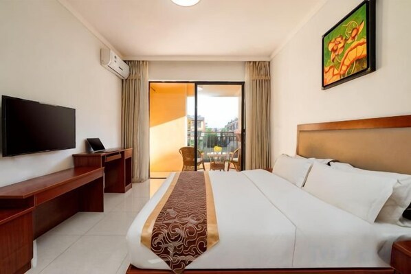 Habitación de hotel con cama, escritorio, televisión y balcón con vistas.