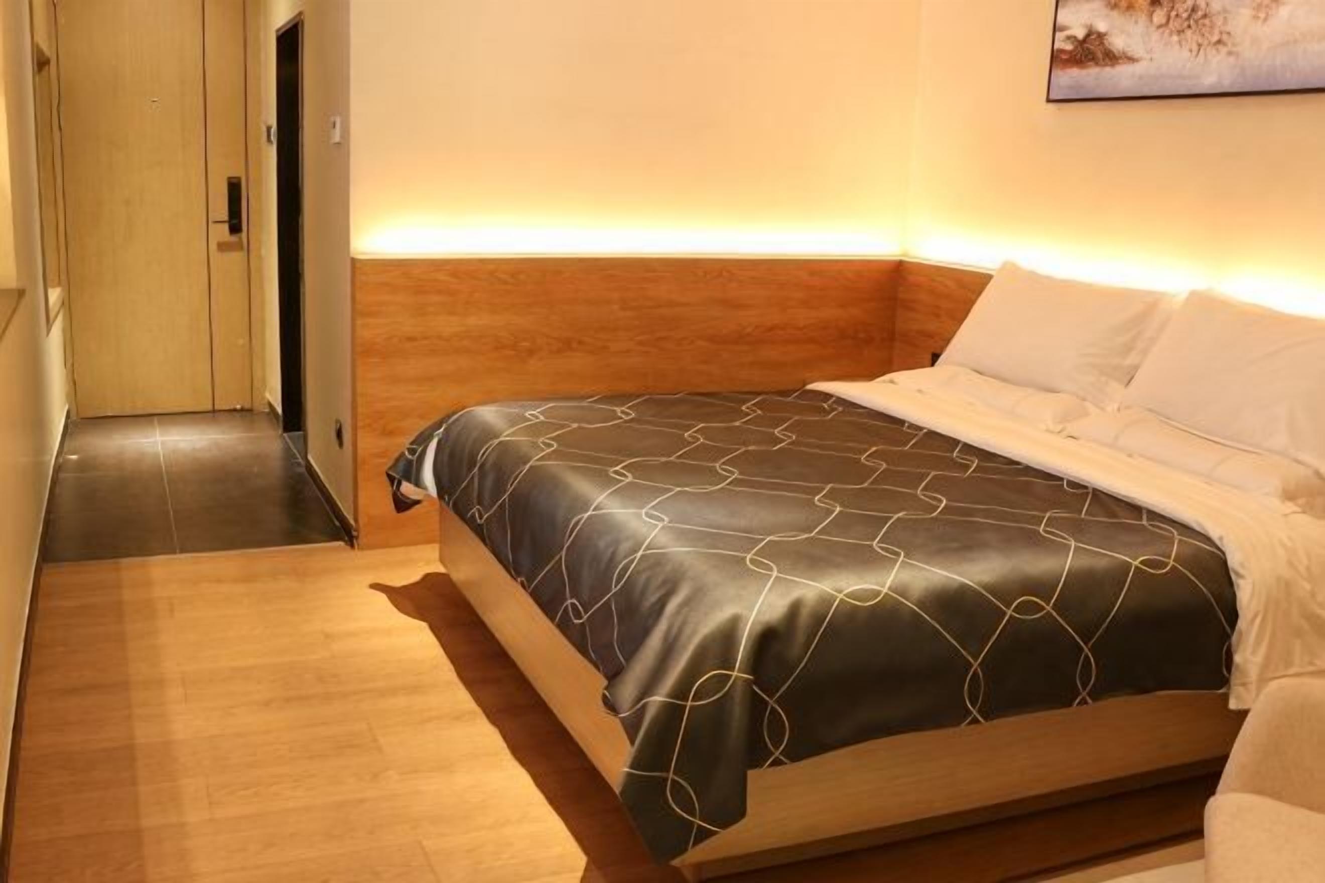 Une chambre d’hôtel avec un lit, une tête de lit en bois et un tableau au mur.