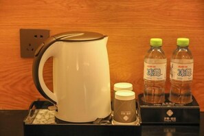 A white electric kettle, two bottles of water, and a box with a logo on a table. - Yicheng Hotel (Maoming China First Beach) (Maoming)