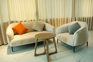 A room with a sofa, a chair, and a small wooden table. - Yicheng Hotel (Maoming China First Beach) (Maoming)