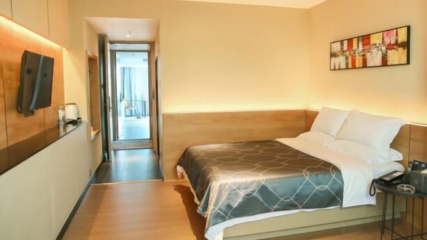 A hotel room with a bed, bedside table, and a painting on the wall.