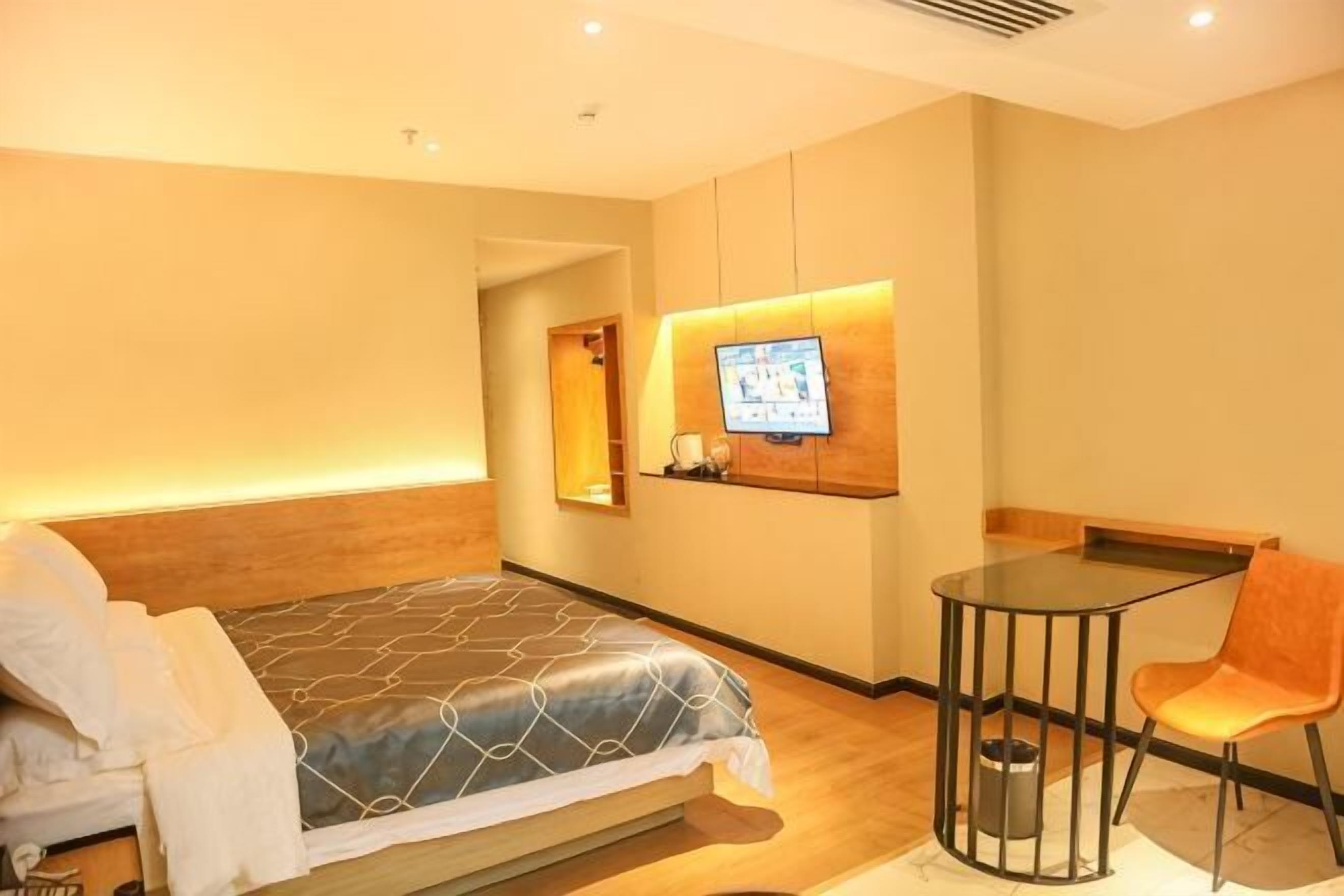 Une chambre d’hôtel avec un lit, un téléviseur fixé au mur, une petite table et une chaise.