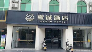 A hotel entrance with a sign reading "Eason Hotel" and two scooters parked in front.