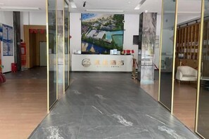 A reception area with a reception desk, a painting on the wall, and a glass partition. - Yicheng Hotel (Maoming China First Beach) (Maoming)