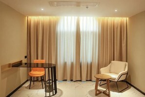 A hotel room with a dining table, two chairs, a sofa, and a large window with curtains. - Yicheng Hotel (Maoming China First Beach) (Maoming)