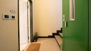 Un couloir avec une porte verte, une porte blanche et une petite plante.
