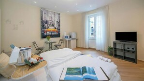 Une chambre d’hôtel avec un lit, un bureau, une télévision et une fenêtre avec des rideaux.