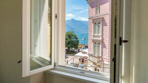 Une chambre d’hôtel avec vue sur un bâtiment rose, un balcon et une étendue d’eau.