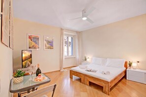 Une chambre d’hôtel avec un lit, un bureau et une chaise, une fenêtre et un ventilateur de plafond.