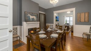 Comedor con mesa de madera dispuesta para seis personas, chimenea y candelabro.