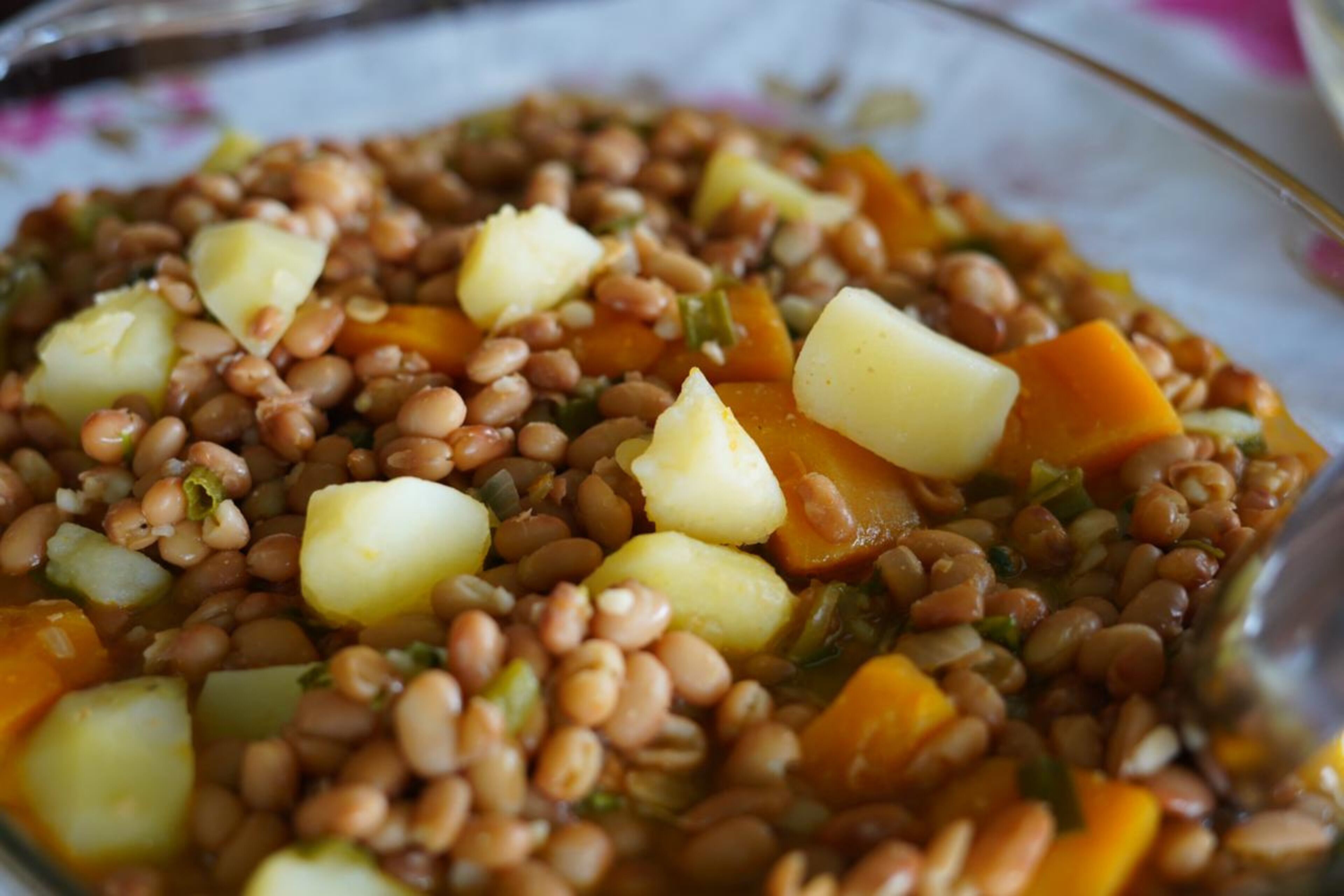 A close-up of a dish with lentils, potatoes, and carrots.