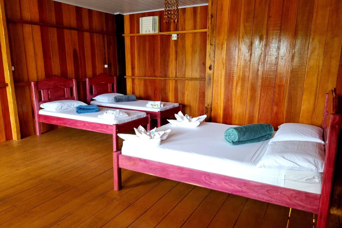Ein Zimmer aus Holz mit zwei Betten, jeweils mit weißen Leintüchern und Handtüchern.