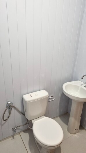 Ein Badezimmer mit Toilette, Waschbecken und Duschkopf.