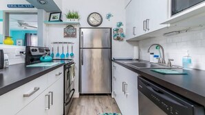 Une cuisine moderne dotée d’appareils électroménagers en acier inoxydable, de meubles blancs et d’un plan de travail noir.