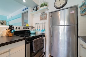 A kitchen with a stainless steel refrigerator, a stove, and various kitchen utensils. - Mid Mari - Gorgeous Nautical Condo Near Beach, Shops & Restaurants- Condo 105 (Pompano Beach)