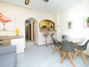 A modern kitchen with a central island, a dining area with a round table and chairs, and a hallway leading to another room. - Eurosol by Interhome (Calpe/Calp)
