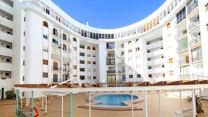 A multi-story hotel with a central courtyard featuring a swimming pool, outdoor seating, and a netted safety area. - Eurosol by Interhome (Calpe/Calp)