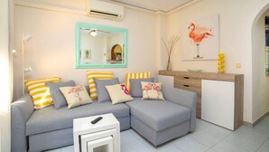 A modern living room with a grey sofa, striped pillows, a small white side table, and a wooden console table with a vase and yellow balls. - Eurosol by Interhome (Calpe/Calp)