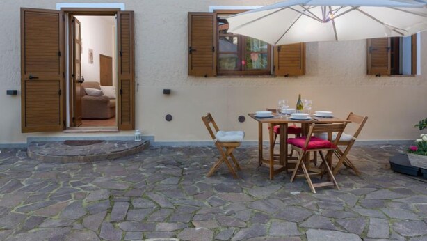 Un patio con piso de piedra, muebles de madera y una mesa lista para comer.