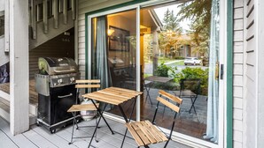 A covered patio with a grill and wooden chairs.