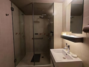 A bathroom with a glass-enclosed shower, a white sink, and a mirror above the sink.