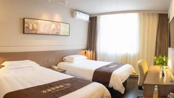 A hotel room with two beds, a desk, a chair, a window with curtains, and a wall-mounted air conditioner.