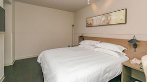 A hotel room with a bed, bedside lamps, a telephone, and a painting on the wall. - Jinjiang Inn Select (Tianshui)