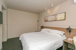 Quarto de hotel com cama, abajures, telefone e um quadro na parede.