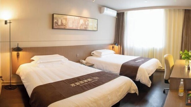 Une chambre d’hôtel avec deux lits, un bureau, une chaise, une lampe et un tableau au mur.
