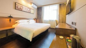 A hotel room with a bed, bedside table, desk, and a TV mounted on the wall. - Jinjiang Inn Select (Tianshui)