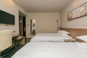 Habitación de hotel con dos camas, un escritorio, una silla, un televisor y un cuadro en la pared.