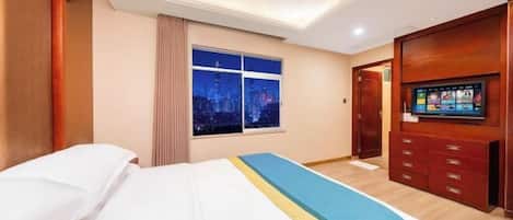 Una camera d'albergo con un letto, una televisione, una finestra vista sulla città e un armadio in legno.