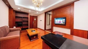 A modern hotel room with a sofa, a coffee table, a TV mounted on the wall, and built-in wooden shelves. - Lilai Business Hotel (Dongguan)