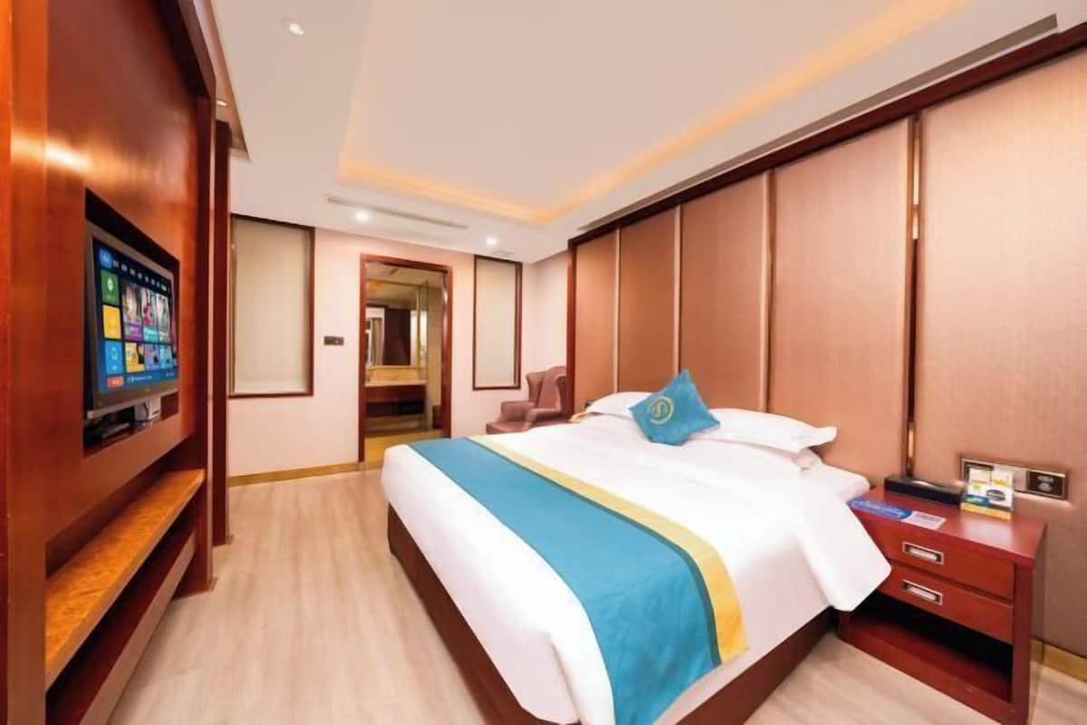 A hotel room with a bed, a TV, a desk, and a wardrobe.