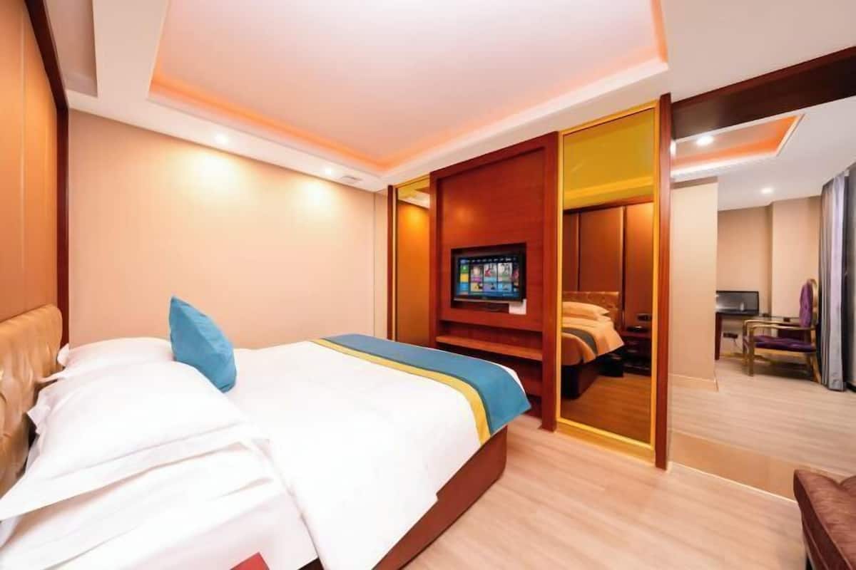 A hotel room with a bed, a television, a desk, and a chair.
