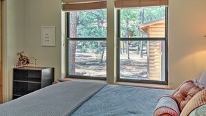 A bedroom with a large bed, a dresser, and a window with a view of a wooden cabin and trees. - 3 Mi to Dtwn: Show Low Retreat w/ 2 Decks (Show Low)
