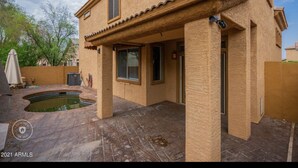 A two-story house with a patio area, a swimming pool, and a covered outdoor seating area. - Beautiful patio home in exclusive Cave Creek (Cave Creek)