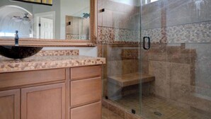 A bathroom with a large mirror, a vessel sink, wooden cabinets, and a glass-enclosed shower area. - Beautiful patio home in exclusive Cave Creek (Cave Creek)