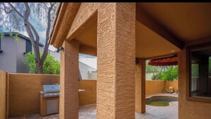 A covered outdoor patio area with stone flooring, a barbecue grill, and a small pool. - Beautiful patio home in exclusive Cave Creek (Cave Creek)