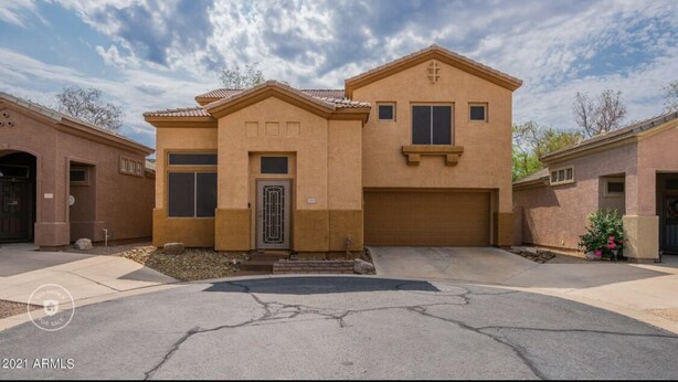 A two-story house with a garage, a front door, and a small porch. - Beautiful patio home in exclusive Cave Creek (Cave Creek)
