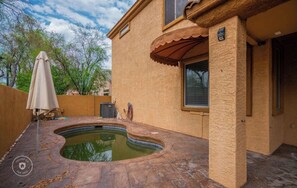 Une maison avec une piscine, un patio couvert et une façade de couleur beige.
