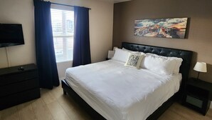 A bedroom with a bed, a TV, a painting, and a window with curtains. - ★Strip views w/amenities! Pool, fitness center, W/D in-unit & FREE parking!★ (Las Vegas)