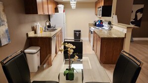 A modern kitchen with granite countertops, stainless steel appliances, and a chandelier. There is a dining area with a table and chairs, and a small island with a sink. - ★Strip views w/amenities! Pool, fitness center, W/D in-unit & FREE parking!★ (Las Vegas)