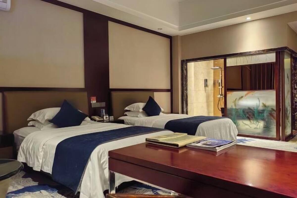 Una habitación de hotel con dos camas, un escritorio de madera y un cuadro grande en la pared.