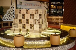 Un área de recepción con una presentación escalonada de cajas, una fuente de agua y dos lámparas.