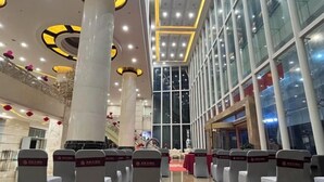 A spacious hall with rows of chairs, large pillars, and a high ceiling with circular light fixtures. - Yongqian Hotel (Yongde)