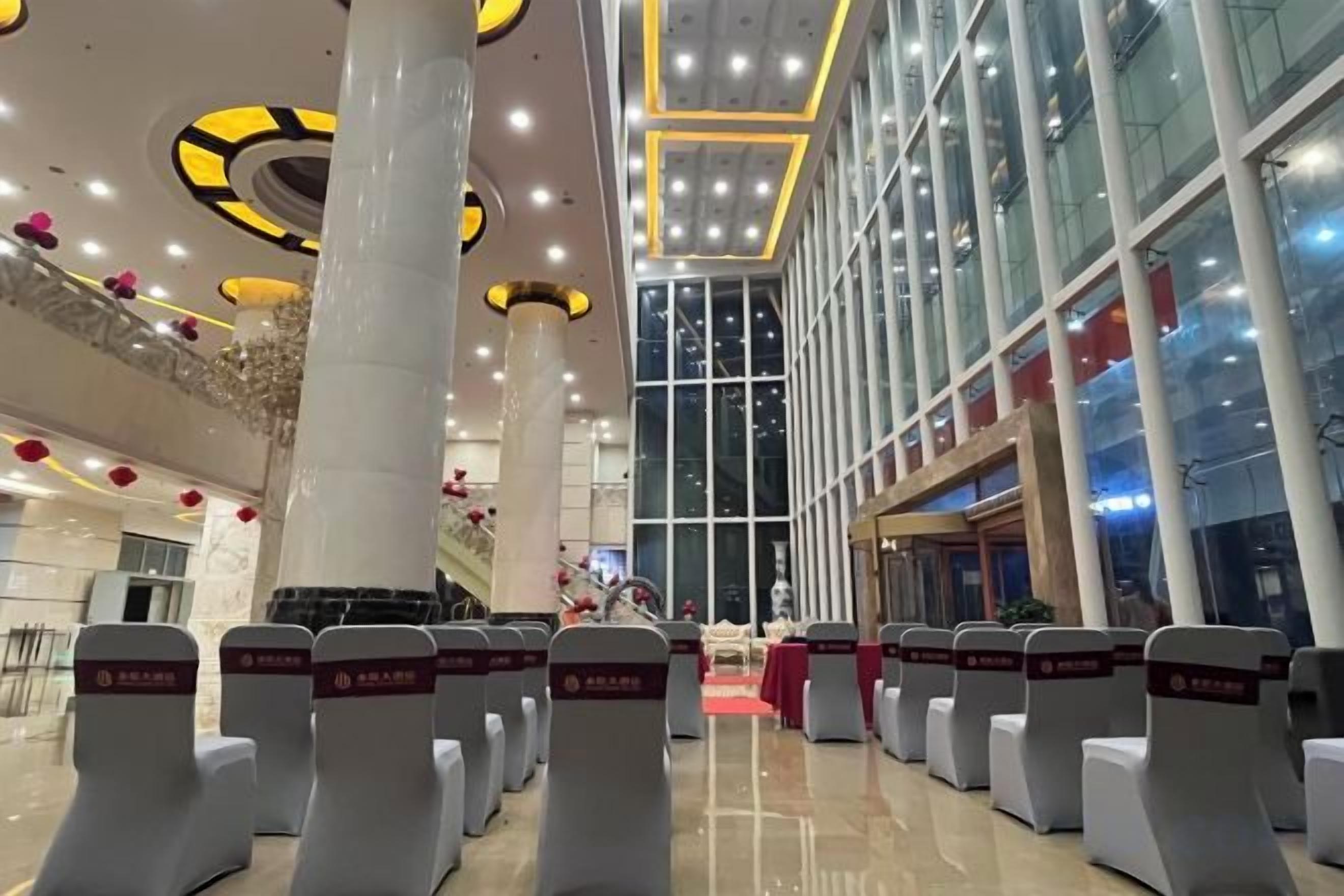 A hotel lobby with rows of seating, large windows, and a high ceiling with circular light fixtures.